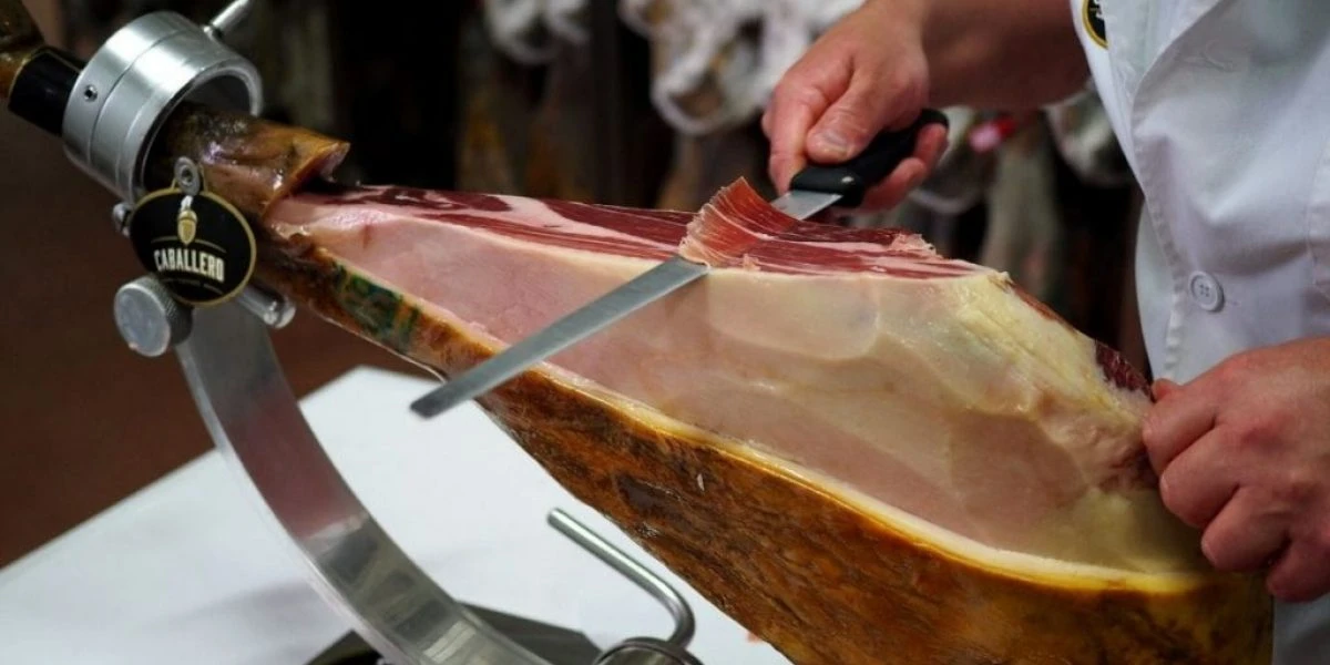 Maestro jamonero cortando una loncha de jamón a cuchillo